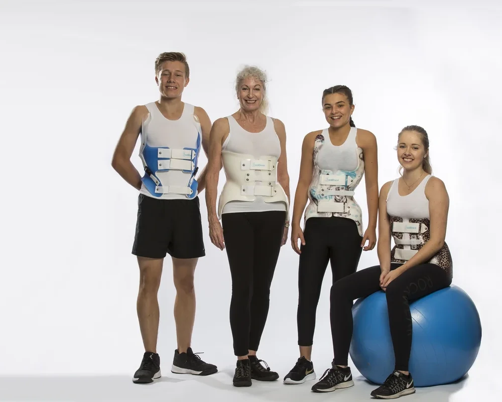 Four ScoliBrace patients, from teenager to adult, wearing their custom scoliosis braces